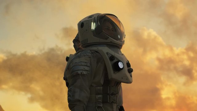 Low Angle Shot of Female Astronaut in the Space Suit Looking Around Alien Planet. Advanced Technologies, Space Travel, Colonization Concept. Shot on RED EPIC-W 8K Helium Cinema Camera.
