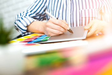 Young graphic designer woman using digital graphic tablet while working at office
