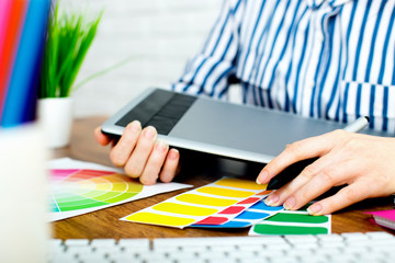 Young graphic designer woman using digital graphic tablet while working at office