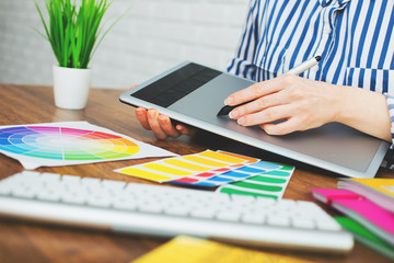 Young graphic designer woman using digital graphic tablet while working at office