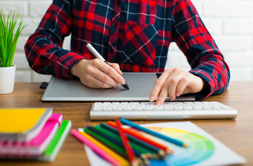 Young graphic designer woman using digital graphic tablet while working at office