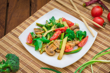 Salad with mushrooms, avocado, tomatoes and greens. Wooden rustic background. Top view