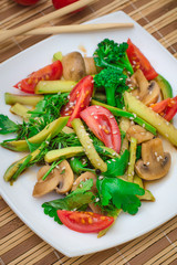 Salad with mushrooms, avocado, tomatoes and greens. Wooden rustic background. Top view