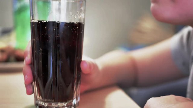 Teenager drinking a glass of refreshing cold fizzy cola drink