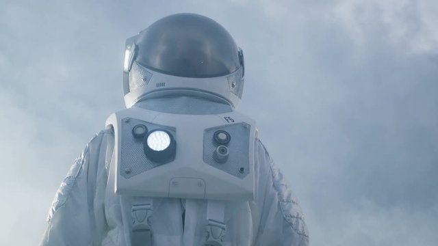 Low Angle Shot of the Brave Astronaut in the Space Suit Looking Around Alien Planet. Blue and Cold Planet. Shot on RED EPIC-W 8K Helium Cinema Camera.
