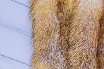 Red fox skin on a gray wooden background. Beautiful fur of a red fox