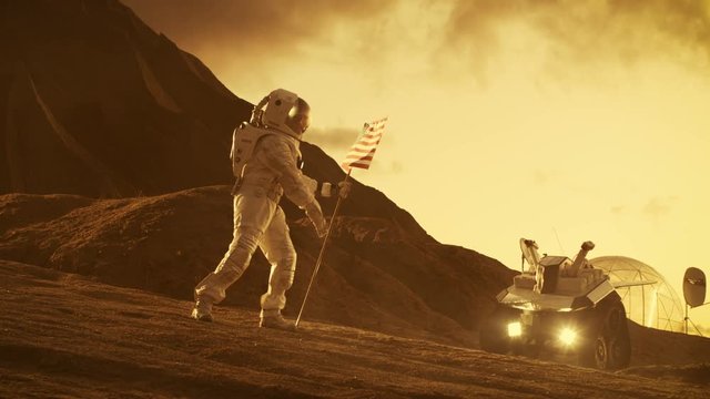 Astronaut Wearing Space Suit Plants American Flag on the Red Planet/ Mars. Patriotic and Proud Moment for the Whole of Humanity. Shot on RED EPIC-W 8K Helium Cinema Camera.
