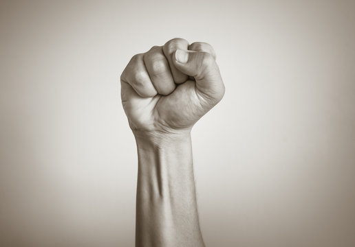 Closeup of fist clenched in the air. Power, victory, revolution concept. 