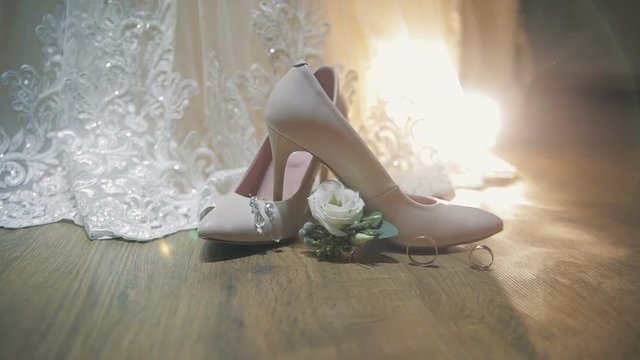 Two wedding rings rolling together near bride's wedding shoes