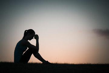 Silhouette of woman sitting alone feeling sad and stressed. 