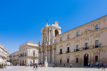 Fototapeta na wymiar ORTIGIA, ITALY - AUGUST 20, 2017: tourists and locals visit the Cathedral Square (Piazza del Duomo) in the island of OrtIgia, historic center of Siracusa, Sicily
