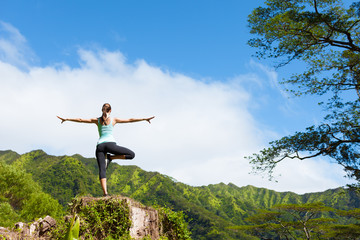 Woman doing a balancing yoga pose on a mountain. 