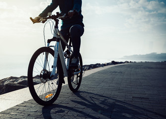 cyclist riding bike in the sunrise coast path