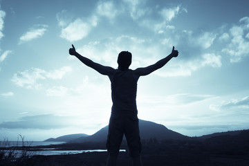 Fototapeta na wymiar Positive feelings. Man standing on a mountain feeling happy, and free. Thumbs up!
