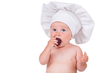 A small child is eating plums in a chef suit on a white background.