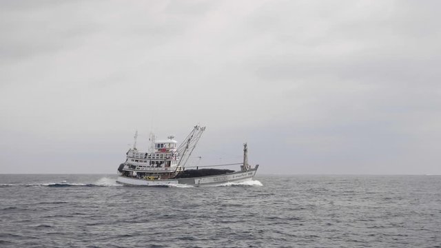 A commercial fishing boat in the sea in slow motion.