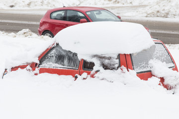 Red car covered snow after snowfall blizzard	