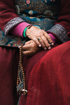 Tibetian  old lady in traditional costume holding mala beads in a hand. Ladakh,India
