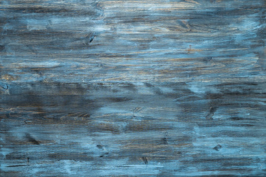 Blue stained wood texture background with a worn distressed effect. Use this weathered wooden textured material as design asset for a wall, floor boards, wallpaper, table surface or abstract backdrop.