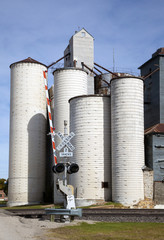 Railroad and gate signal next to grain elevators in Kansas, US, 2017.
