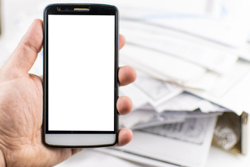 A man's hand holds a mobile phone against a background of scattered documents. mock-up.