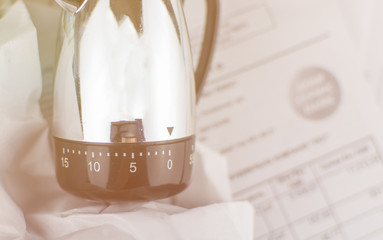 The concept of deadline. Mechanical timer at zero against the background of scattered documents....