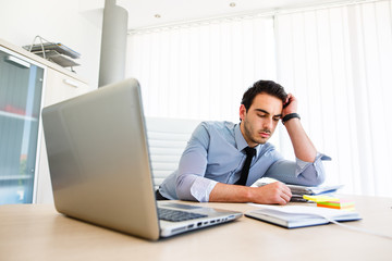 Lonley tiresome businessman spending time at work