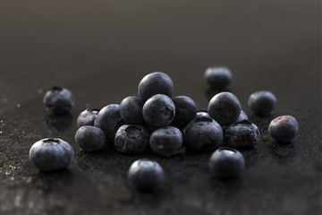 Isolated juicy blueberries on dark background with drop of water