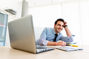 Optimistic successful businessman at workplace