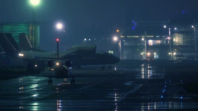 Business jet maneuvers the runway after landing at night. Back view 