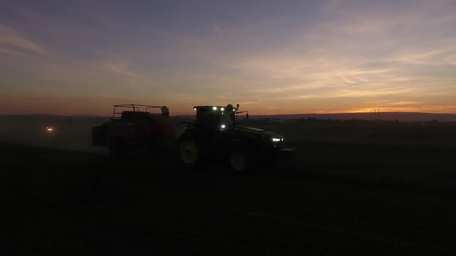 aerial low profile of bale dropping from hay baler at night