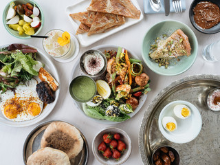 Full spread of healthy mediterranean brunch food. Eggs, pita, olives, salad, berries.