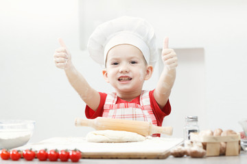 Boy with chef hat preparing the pizza dough