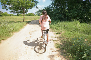 Young female cycles through the countryside of Burma
