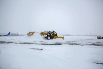 Clearing airport from snow during snow storm. clearing runway from snow. Clearing snow with bulldozers from airport aprons.