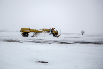 Clearing airport from snow during snow storm. clearing runway from snow. Clearing snow with bulldozers from airport aprons.