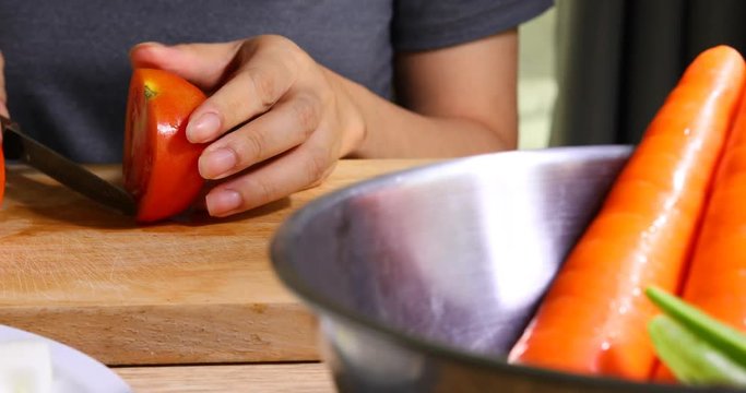 woman cooking food sliced tomato with knife on wooden chopping board