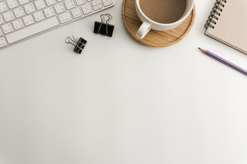 White office desk table with blank notebook, computer, supplies and coffee cup. Top view with copy space. Flat lay.