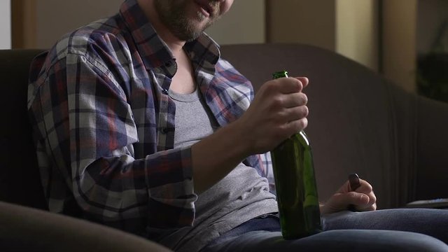 Alcoholic opening beer bottle with fork on home sofa, unhealthy habit addiction