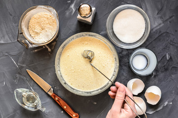 cooking  of Russian dishes pancakes: eggs, milk, flour, butter, salt. Hand stirring dough