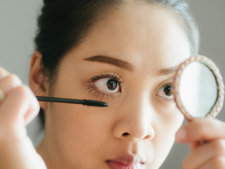 Woman is putting make up mascara on her eyelashes.