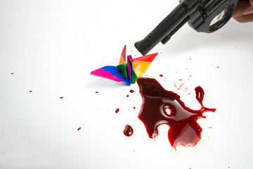 Hands using using the gun to kill origami bird, abstract meaning of freedom stealing, homosexual...