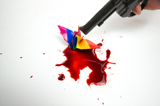 Hands using using the gun to kill origami bird, abstract meaning of freedom stealing, homosexual law, Gay conceptual images