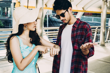 Asian woman is pointing at a wristwatch with argument feeling to boyfriend