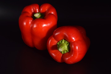 Bright red peppers on a seamless black background. 