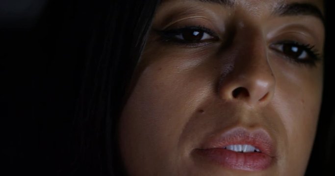 4K Extreme close up on face of woman looking at computer screen late at night
