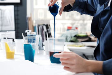 Young female artist painting abstract acrylic canvas in studio