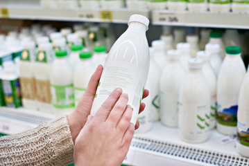 Woman chooses milk and dairy products at store