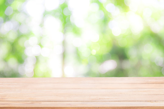 Empty wooden table with Defocus nature green bokeh, abstract nature background.