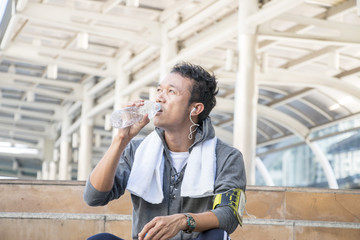 Sporty man is drinking a bottle of water after exercising 